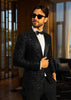 Man wearing a black sequin tuxedo with sunglasses indoors.
