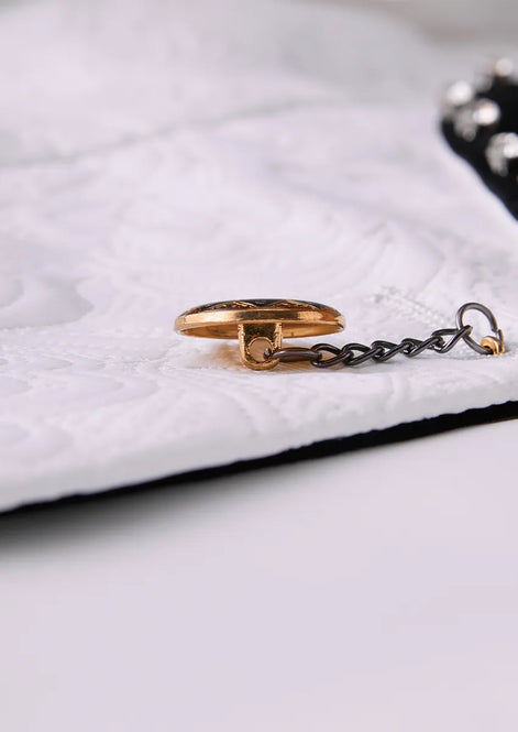 Detail of metallic chain-link button closure on white tuxedo