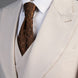 Close up of wide peak lapel and chocolate brown tie on beige suit jacket |
