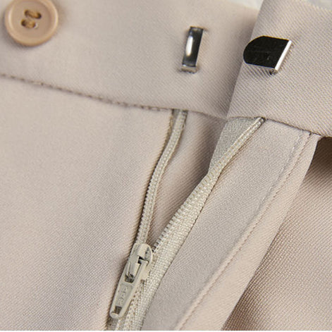 Close up of waistband and metallic closure on matching beige trousers