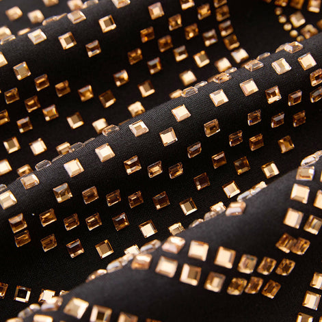 Macro view of amber-gold emerald-cut crystals on black obsidian fabric