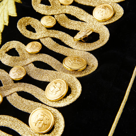 Detail of gold rope frogging and metal buttons on black velvet jacket
