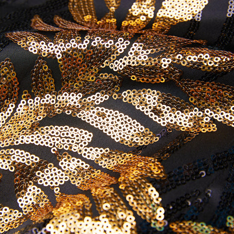 Detail view of intricate gold sequin feather pattern on black fabric