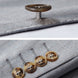 Detail view of horn-patterned buttons on light grey suit sleeve |