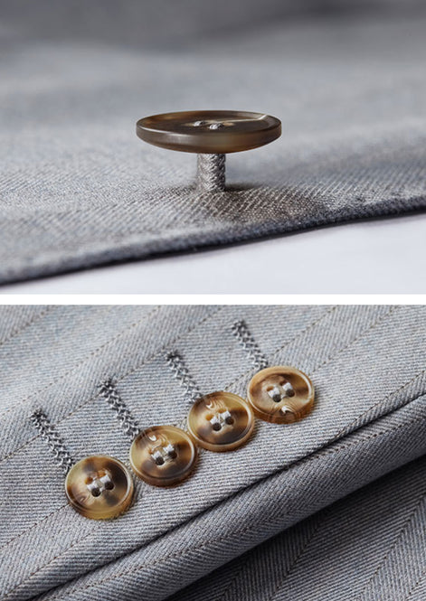Detail view of horn-patterned buttons on light grey suit sleeve |
