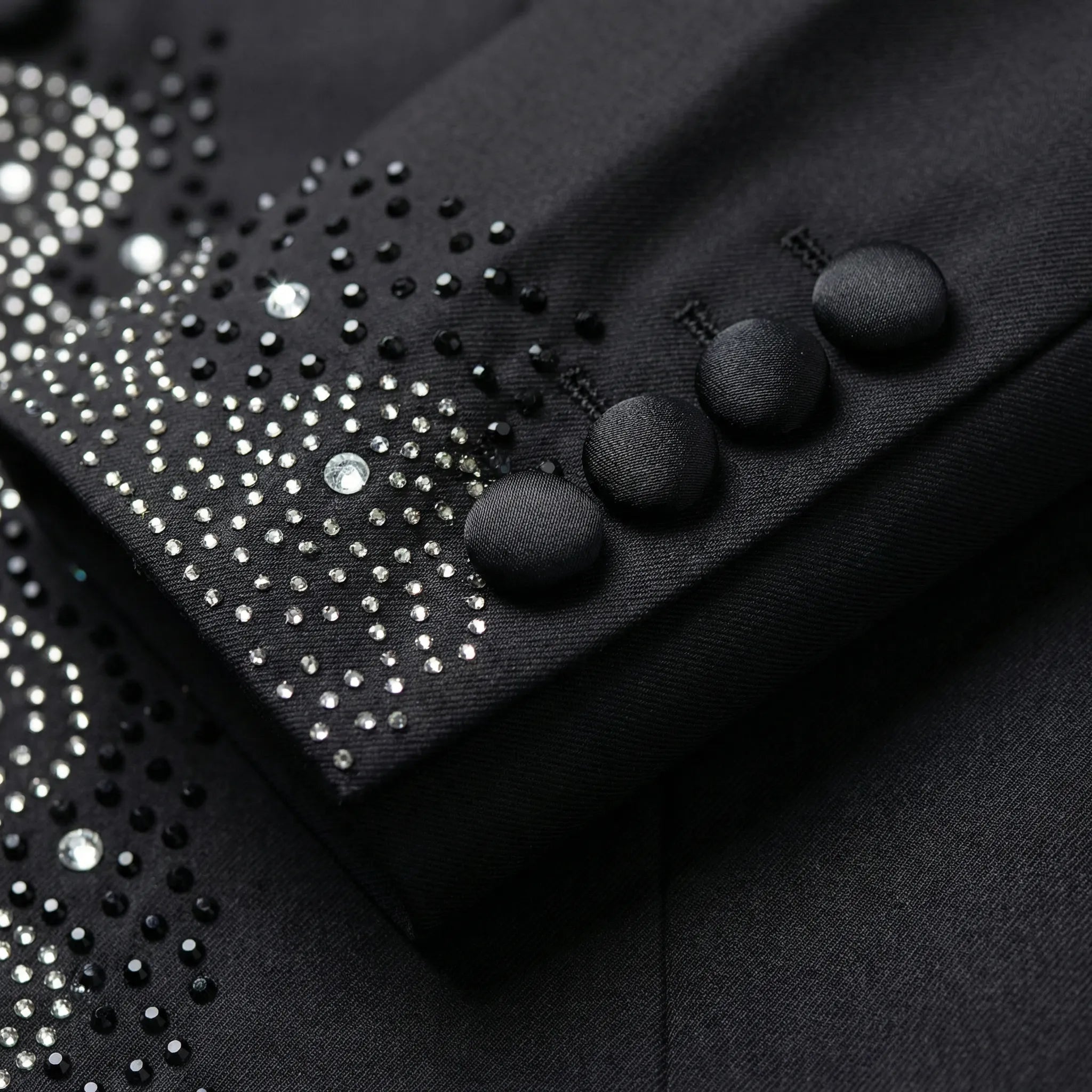 Close up of hand-placed onyx crystals and satin-covered buttons on tuxedo sleeve