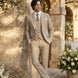 Man in a beige suit standing in an outdoor setting with floral arrangements and stone architecture.