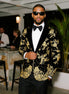 Man wearing a black tuxedo with gold embroidery in an indoor setting