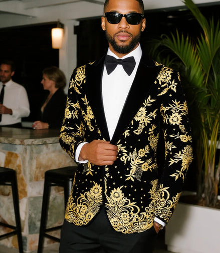 Man wearing a black tuxedo with gold embroidery in an indoor setting