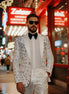 Man in a white patterned suit standing in front of a Zales jewelry store.