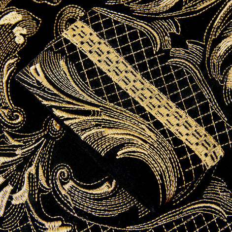 Close up of gold scroll embroidery detail on black velvet jacket